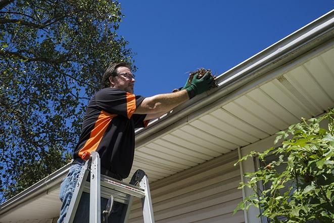 a roofer repairing a damaged gutter on a house in Big River, CA